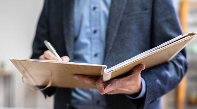 Immobilienmakler mit Unterlagen bei der Objektbesichtigung Immobilienmakler prüft Unterlagen während einer Objektbesichtigung